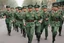 Placeholder: Soldiers marching in formation; military parade; tight formation; shoulder to shoulder; marching along a street; green uniforms; medals and insignia; weapons in hands;