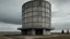Placeholder: Un edificio cilíndrico de hormigón gris y cobre oxidado, perforado por óculos irregulares, erguido como un observatorio industrial en una llanura despejada bajo un cielo nublado