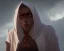 Placeholder: A white hooded robe covered a brown woman with a sleepy look in her eyes has red dreadlocks and above her head is a golden halo. From behind her, two black demon-like hands with long fingers, the right one pointing to the sky and the left one to the floor.