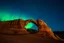 Placeholder: realistic natural land bridge rock formation in a desert at night with a brilliant norther lights display in the distance, starry night, aroura borealis,