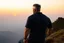 Placeholder: a brawny man with grey hair views sunset from a cliff