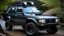Placeholder: A unique off-road vehicle that is a blend of a 1997 Subaru Legacy and a 1985 Audi Quattro. The vehicle features rugged off-road tires, LED lights, a winch, and an expedition roof rack. The design combines the distinctive elements of both cars, creating a powerful and versatile off-road machine with a custom appearance. The car is set in an adventurous outdoor setting, showcasing its capability and robustness in challenging terrains.