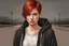 Placeholder: Woman with bright, short red hair, brown eyes, wearing a black hoodie, realistic