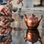 Placeholder: The reflection of a child on the surface of an old copper teapot