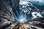 Placeholder: at the base of the rocky mountain peninsula, a great whirlpool waterfalls into deeper unknown depths