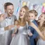 Placeholder: Photograph of a happy couple with kids celebrating with silver party decoration.