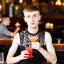 Placeholder: Russian guy boyish boylike short man's haircut boyish features in black girlish lacy cocktail dress in restaurant