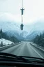 Placeholder: surreal mountain road seen through a dirty truck front window, dirty blue snow and wind, virgin mary hanging