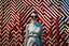 Placeholder: Front profile full body photography, in font of a rusty billboard, a hip hop 80's british model woman with 50's haircut, in a white and red zig zag stripes turtleneck dress and large sunglasses, 80 degree view, art by sergio lopez, natalie shau, james jean and salvador dali