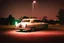 Placeholder: Coche Cadilac americano en mitad de la noche tan sólo iluminado por una farola y los faros del coche, imagen al estilo del fotógrafo Hugo Alonso