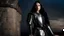 Placeholder: A Beautiful slender caucasian teen female fashion model with long shiny black hair. She is wearing medieval armor. She is standing next to a castle wall at night. The sky behind her looks threatening and ominous. She is looking at the viewer.