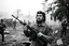 Placeholder: image of Che Guevara standing with heavy gun in hand in a fighting area