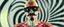 Placeholder: blissfull genious, cyber jobe, flying yoga magic , lawn mover man movie character, portrait of upper body of cool transparent guy made with nano tape and with shades and mustache and bald head, saw blade beholder eye tyrant flating beholder kin with eyes on each saw blade tooth saying something profound, hypnotic zebra twirl background, with chrome reflections, like he is floating in a giger cartoon