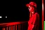 Placeholder: woman with a red baseball hat. leaning on a wooden balcony.night time. studio lightining.