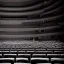 Placeholder: one chair on stage in spotlight close up view facing empty audience at a dark and empty symphony hall