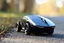 Placeholder: wireless computer mouse with four car wheels driving on the right side of a road