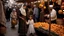 Placeholder: A full-length Palestinian girl wearing an embroidered dress and a white embroidered shawl buys oranges from an old seller wearing a keffiyeh in the market of Jerusalem, 100 years ago, at night with multi-colored lights reflecting on her.