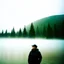 Placeholder: A polaroid photo of a group of fir trees in the background and a high hill in the distance. A person. A lake. The surface below is in a pastel color. Fog is present.