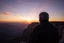 Placeholder: a large man with grey hair views sunset from a cliff