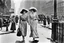 Placeholder: in 1920 two women walking down the street beside each other in nice dresses and hats in New York, Madison Square, high quality, intricate details, realistic