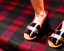 Placeholder: Red plaid slippers on black bearskin rug,log cabin walls, stone fireplace