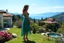 Placeholder: very beautiful lady with beautiful midi green- silver,jeweled lace skirt and pretty same material top with curvy hair high heels standing in a nice villa yard with trees flowers ,in country side in floor of beautiful mountains ,sea with ships ,water falls,16 by 9