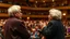 Placeholder: Two Elderly pensioners singing on a concert hall stage in front of a large audience. Photographic quality and detail, award-winning image, beautiful composition.