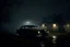 Placeholder: on a very dark and heavy thick foggy night a lone car drives away from an dark decaying and neglected house, set in the 1960s era