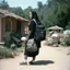 Placeholder: (high res photo by Russ Meyer) Clara, the tattooed free spirit, gangsta nun, burdened with two backpacks, one on her back and one on her front. Is she moving from one house to another or embarking on a vacation to camp? Difficult to say. The constant pressure to keep those worlds coming. The weirder, the better. The weight of the backpacks, the burdens she carries, both physically and metaphorically. Clara seeks solace in the freedom of movement.