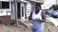 Placeholder: woman hands the bundles of cash her mobile phone provider's located across the street from an boarded up liquor store