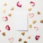 Placeholder: A photo of a white card, 5.5 by 4.25 inches. The card is vertically positioned on a beautiful white surface, positioned between rose petals and litte golden hearts.