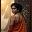 Placeholder: A divine South Asian woman stands in quiet grace, draped in a designer saree of earthy clay tones, evoking the warmth of Bengal soil. Her modern blouse features a deep back cut and minimalist straps, blending tradition with contemporary elegance. Her teary eyes shimmer with emotion, her serene face framed by soft curls and a subtle bindi. Behind her, a carved wooden door with intricate floral and geometric patterns glows in the misty golden light of Diwali. A tall palm tree looms through the fog
