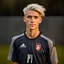 Placeholder: 85mm DSLR color photography of a very detailed headshot fitting all of head and hair in frame. 18-year-old Austrian soccer player, and with no facial hair and has no facial hair, has short length straight white hair with a small smile, grey background