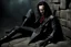 Placeholder: Action shot of Tom Hiddleston as Alucard from the live action "Hellsing" movie based on the anime of the same name. He is sitting, arms chained to a dungeon wall. He appears to be corpse wearing black wrappings that cover all except his head, feet, and hands. His straight, black hair hangs to the floor. A vague smile is on his gaunt face.