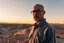 Placeholder: man looking like "Walter White" in breaking bad tv show, bald and goatee glasses, standing on a desert hill in sunset, panorama picture with long shadows, he is standing a long way back perspective
