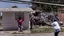 Placeholder: woman hands the bundles of cash her mobile phone provider's located across the street from an boarded up liquor store