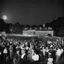Placeholder: [very impressive high res masterpiece in Kodak Eastman 5247, scene by László Krasznahorkai] In the second month of that summer all the school gathered again at the Great House to celebrate the Moon's Night and the Long Dance, which that year fell together as one festival of two nights, which happens but once in fifty-two years. All the first night, the shortest night of full moon of the year, flutes played out in the fields, and the narrow streets of Thwil were full of drums and torches, and the