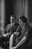 Placeholder: Up close Black and white photo of a serious couple sitting for portrait shoot in the 1920s