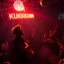 Placeholder: "MR Kukrunk" is Benny, and "DJ Roy" in a disco, dancing, "MR Kukrunk" on sign wall, disco light, strobe, smoke. disco ball, 1000 dancing people