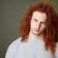 Placeholder: teen, male, with long red curly hair, head shot, model, real photo, soft lighting