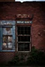 Placeholder: filling the composition is the side of an old brick building, with windows, a doorway at the bottom, and worn out painted sign across the top