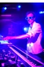 Placeholder: French cool synth player, he is called "Jean-Maurice Brûlée" performing at dance club, his name is "Jean-Maurice Brûlée" , white and blue Neon lights and smog, and "URANIUM" big sign on the wall, he is playing on synthesizers on stage with lot of laser beams and wearing black sunglasses, an earth is projected in background