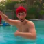 Placeholder: homme cheveux bruns piscine a dubai boit champagne maillot rouge