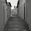 Placeholder: Street of a town on an Italian island in summer, with stairs and arches, decadent tone, real photography, photography taken with a Leica camera and 50 mm lens, following the style of the 'Ripley' series, black and white photography, toned 50s tones