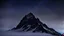 Placeholder: looking up at the tallest single mountain sharp face rising out of the misty foreground into the clear night sky background.