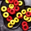 Placeholder: Yellow and red and black donuts on a plate on a black table