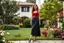 Placeholder: very beautiful lady with beautiful midi dark black-red skirt and top with curvy hair sports shoes standing in a nice villa yard with trees flowers ,16 by 9