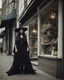 Placeholder: full-length, young woman dressed like a modern-day witch, floaty clothing, with dark hair, outside a shop