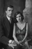 Placeholder: Up close Black and white photo of a serious couple sitting for portrait shoot in the 1920s