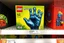 Placeholder: Lego box on display at a toy store shelf, LEGO™️ box labeled "BEKSINSKI", image on box is a nihilistic six fingered hand made out of Lego blocks with nightmarish faces on the fingertips, sinister, pronounced clear LEGO block raised pip textures on all surfaces, unsettling juxtaposition of lego fun and Zdzislaw Beksinski's nightmare surreal art